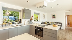 A modern kitchen with a central island, built-in oven, and large windows. - Vikings Annexe, Minehead (Minehead)