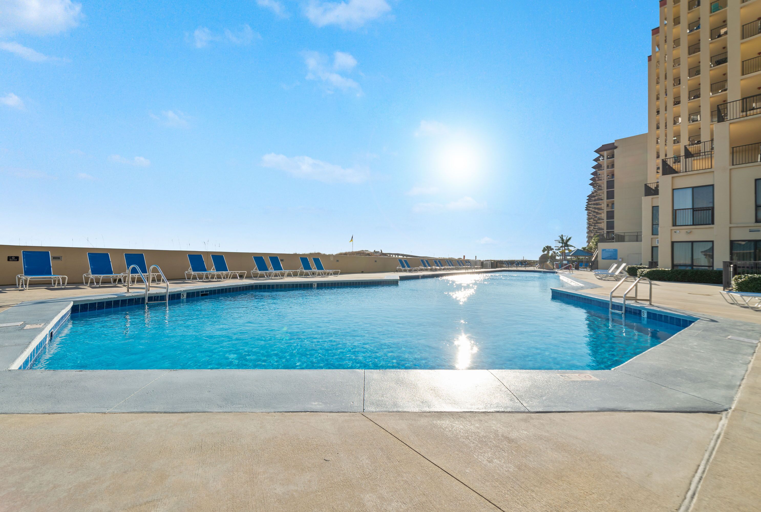 A swimming pool with lounge chairs and a building in the background.