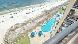 A beach view with a pool area, lounge chairs, and umbrellas. - LUXURY PHOENIX UNIT, GREAT FOR FAMILIES, TONS OF AMENTIES (Orange Beach)