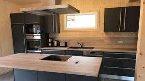 Een moderne keuken met een centraal eiland, inbouwapparatuur en een raam boven de spoelbak.