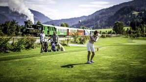 Een golfbaan met een trein op de achtergrond.