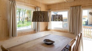 Une salle à manger en bois avec une grande table, des chaises et un luminaire suspendu.