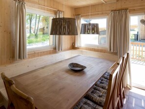 A wooden dining room with a large table, chairs, and a hanging light fixture.
