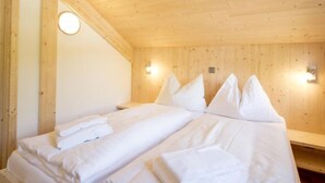Une chambre dans un chalet en bois, équipée de deux lits, chacun avec du linge de lit et des oreillers blancs.
