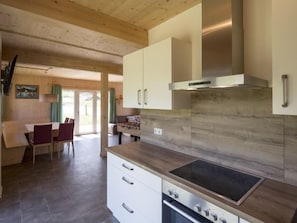 A modern kitchen with wooden cabinets, a built-in stove, and a dining area with a table and chairs.