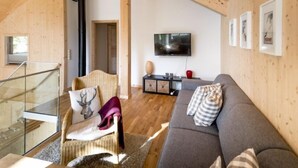 A modern living room with a wooden ceiling, a grey sofa, a television, and a staircase leading to an upper level. - Premium mit 5 SZ, Sauna oder IR-Sauna by Interhome (Sankt Georgen am Kreischberg)