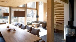 A modern interior with a long wooden table, comfortable seating, a fireplace, and large windows. - Premium mit 5 SZ, Sauna oder IR-Sauna by Interhome (Sankt Georgen am Kreischberg)