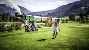 Ein Golfplatz mit einem Zug im Hintergrund.