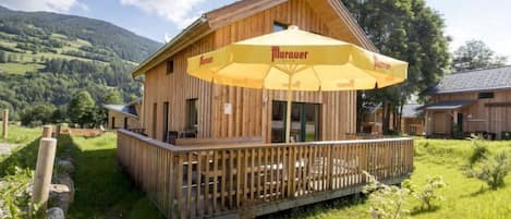 A wooden building with a balcony and a large yellow umbrella.