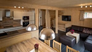 Una cocina moderna con armarios de madera y electrodomésticos de acero inoxidable, un comedor con mesa y sillas de madera, y una sala de estar con sofá y televisor de pantalla plana.