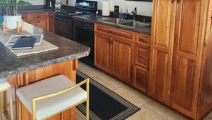 A kitchen with wooden cabinets, granite countertops, a black stove, and a microwave.