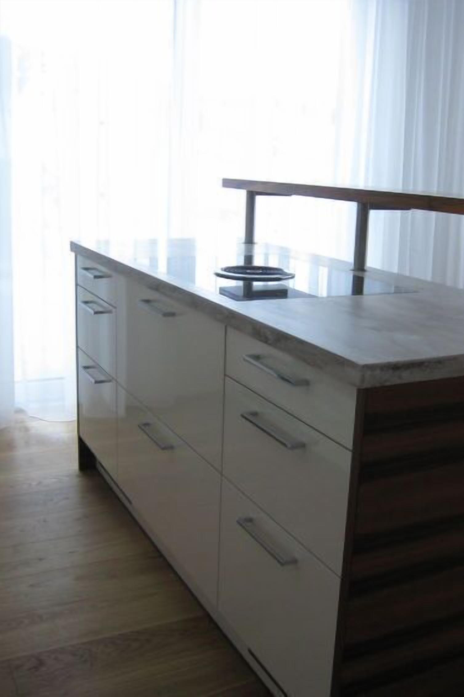 Une cuisine avec un plan de travail en bois, des placards blancs et une fenêtre avec des rideaux.