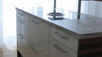 Une cuisine avec un plan de travail en bois, des placards blancs et une fenêtre avec des rideaux.