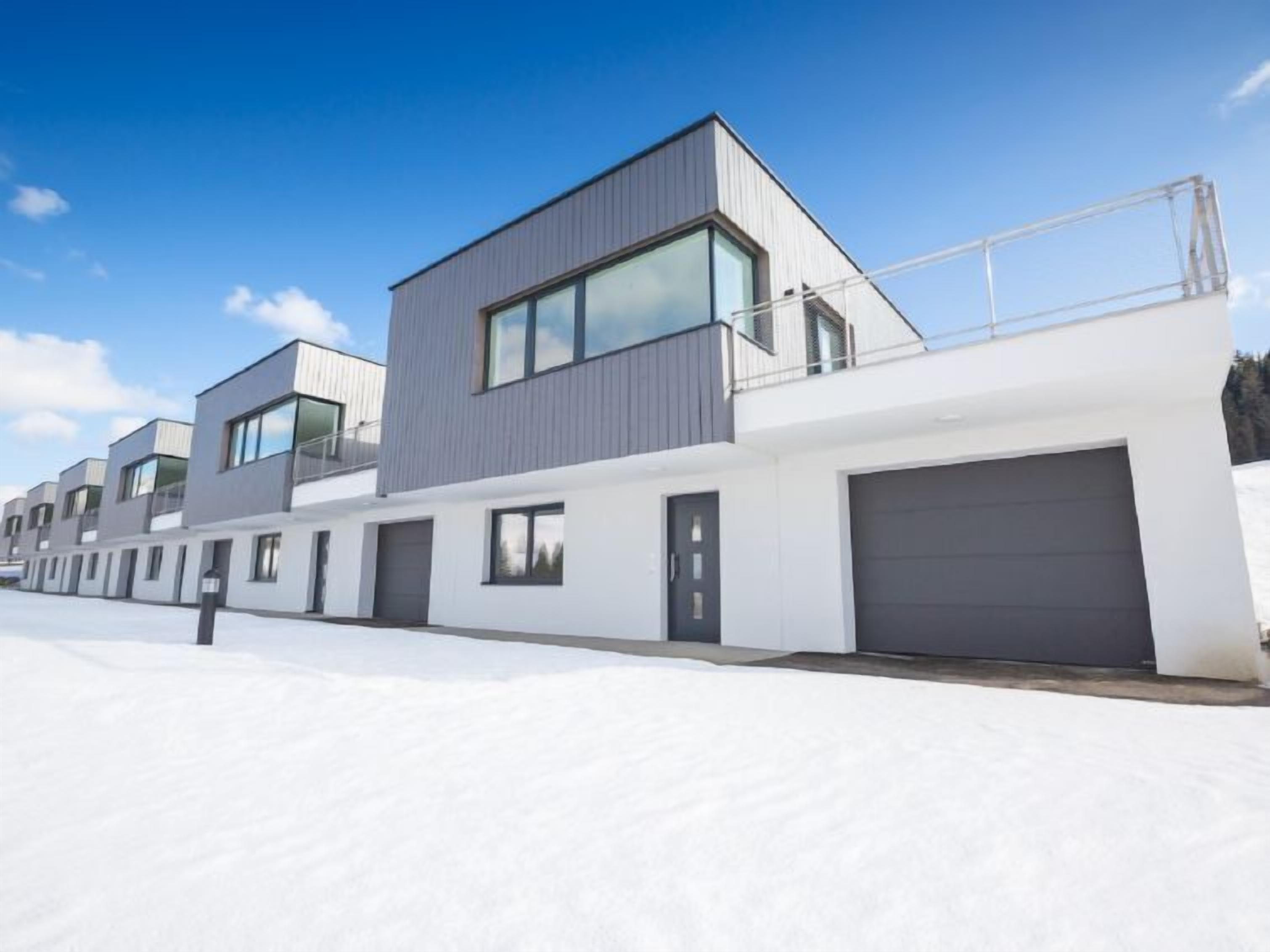Un immeuble résidentiel moderne doté d’un toit plat, de grandes fenêtres et d’un garage.