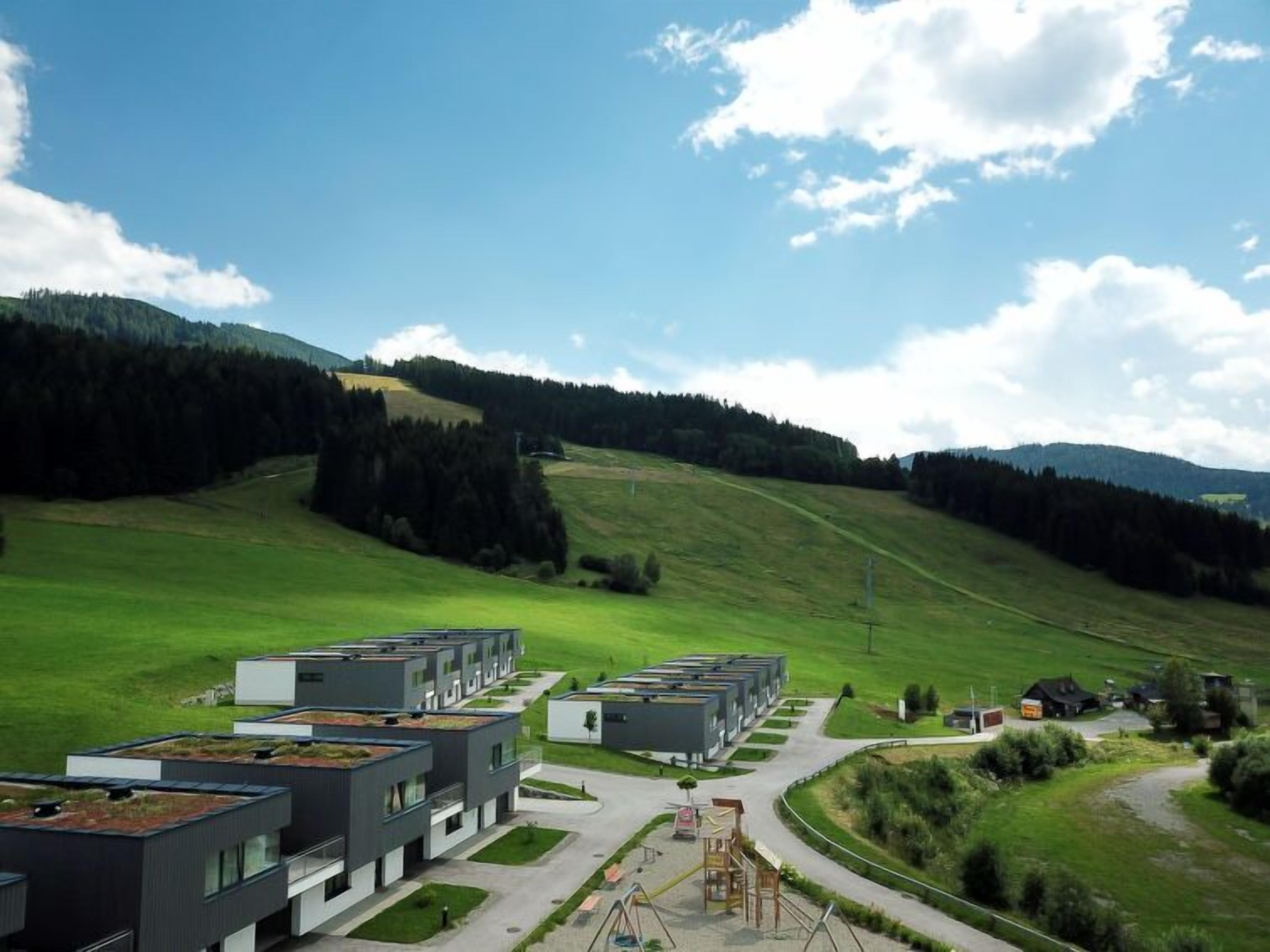 A modern residential complex with multiple apartment buildings, green spaces, and a playground.