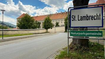 Un panneau de signalisation indiquant « St. Lambrecht » et « Naturparkgemeinde », avec un bâtiment en arrière-plan.