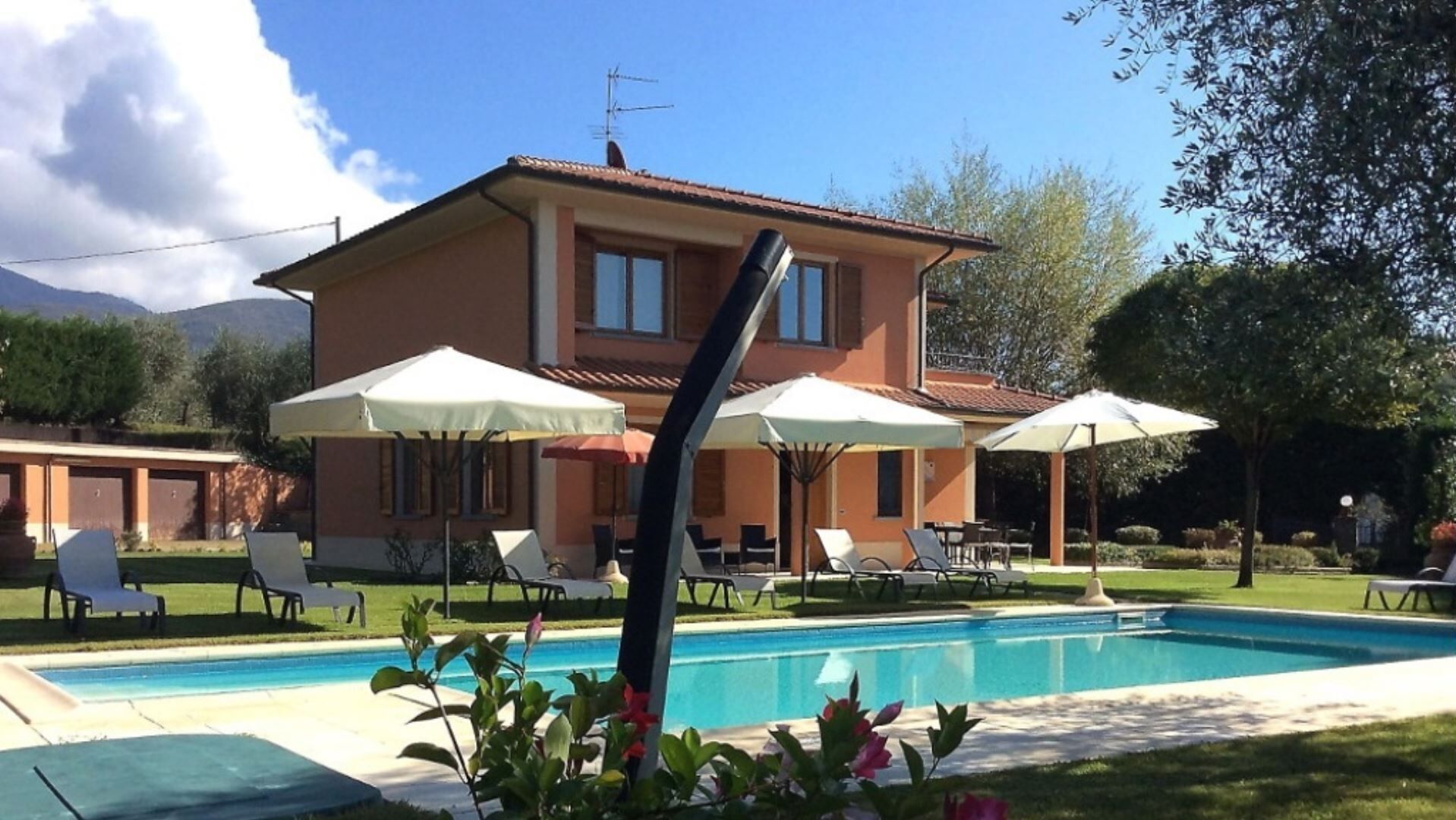 A two-story house with a swimming pool, outdoor seating, and a mountain backdrop.