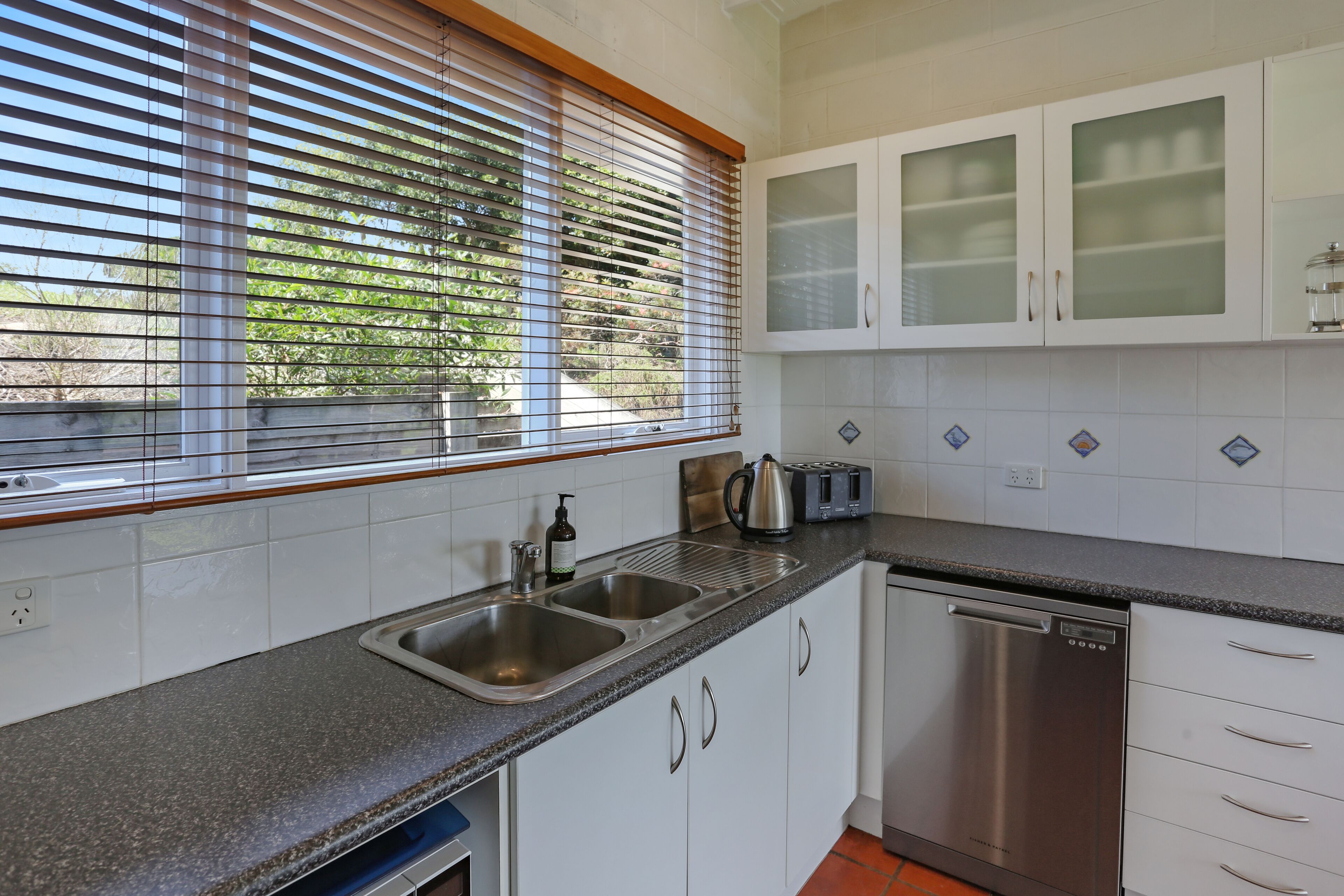 A modern kitchen with a granite countertop, stainless steel appliances, and white cabinetry.