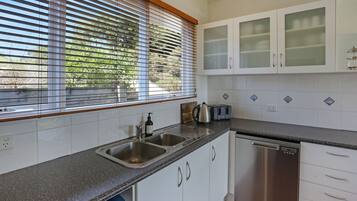 A modern kitchen with a granite countertop, stainless steel appliances, and white cabinetry.