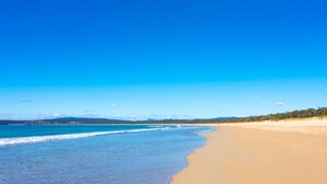 A wide beach with clear blue water and a sandy shore. - Cordova - Perfect Summer or Winter Getaway (Merimbula)