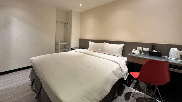 A hotel room with a bed, a desk with a chair, a shower, and a telephone. - Good Day Inn (Taipei)