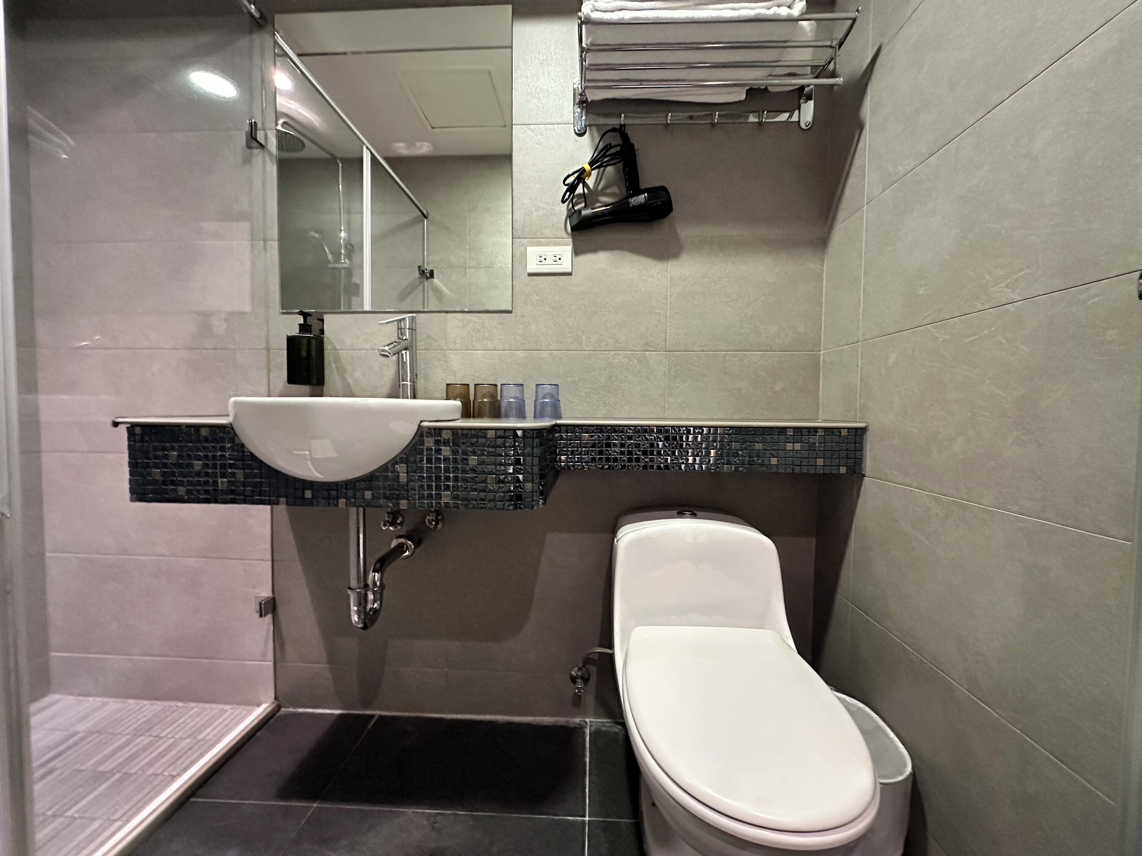 Un baño moderno con un lavamanos blanco, un inodoro y una zona de ducha.