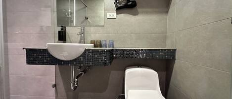 Un baño moderno con un lavamanos blanco, un inodoro y una zona de ducha.