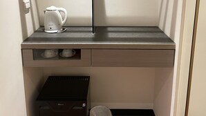 A compact kitchenette with a built-in oven, a coffee maker, and a trash bin. - Good Day Inn (Taipei)