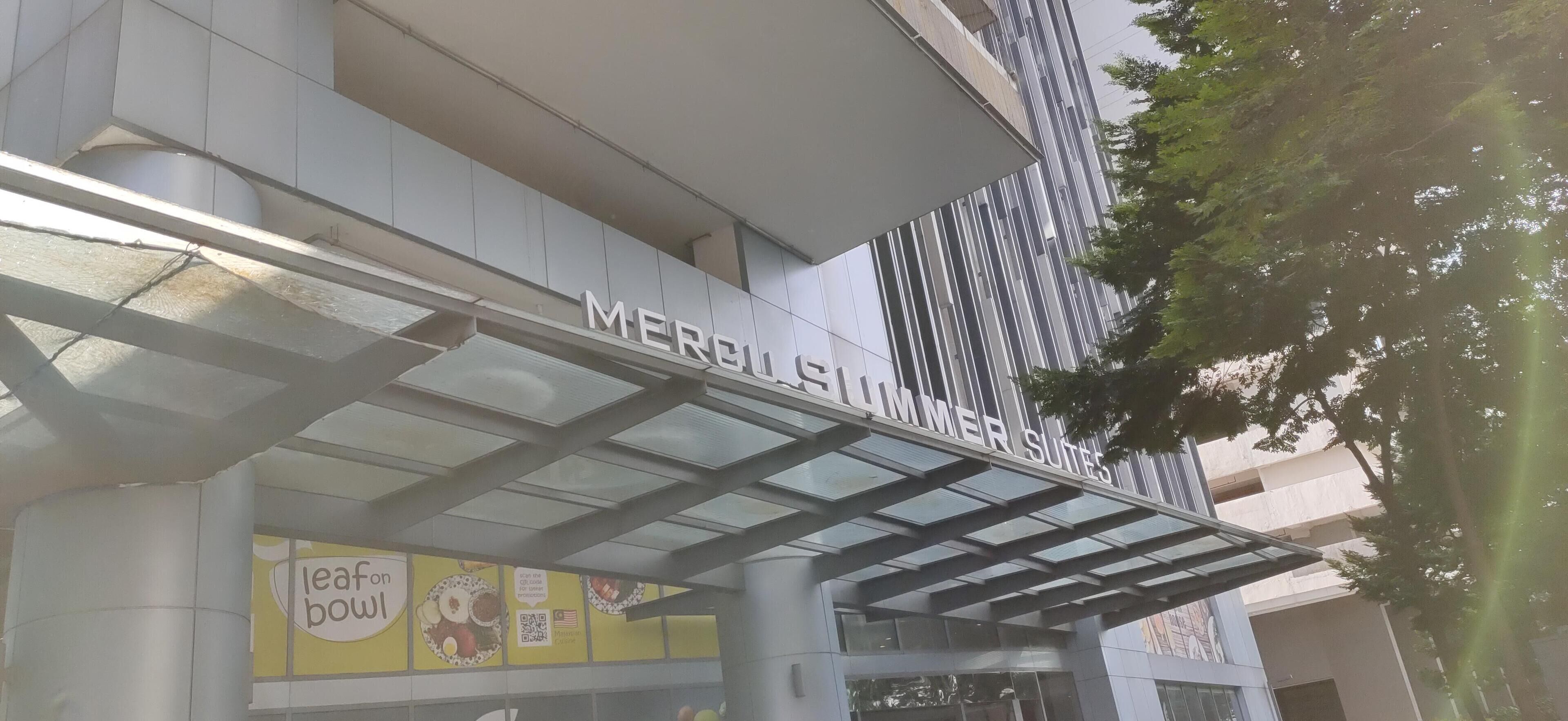 Un bâtiment moderne portant l'enseigne « MERCHANDISER SUITES », ce qui indique qu'il s'agit d'un espace commercial.