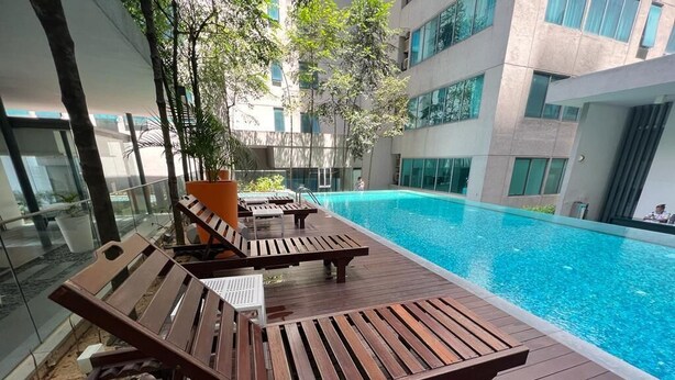 Un espace aménagé au bord de la piscine, avec des chaises longues en bois et une vue dégagée sur la piscine.