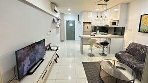 Un salon moderne avec un téléviseur à écran plat, un canapé, une table basse en verre et un ventilateur de plafond.
