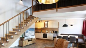 Ein geräumiger Wohnbereich mit einer Holztreppe, einem Essbereich und einer Küche.