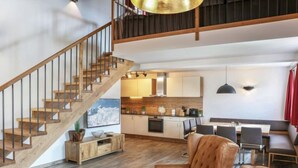 Un vaste espace de vie comprenant un escalier en bois, un coin repas et une cuisine.