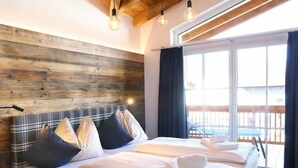 Un lit double avec une tête de lit en bois, deux tables de chevet et une grande fenêtre avec des rideaux.