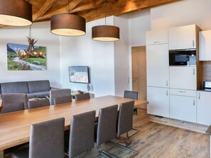 Una cocina moderna con armarios blancos, una mesa de comedor de madera y un sofá gris.