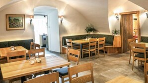 Ein gemütliches Restaurant mit Holztischen und -bänken, einem Gemälde an der Wand und einer Pflanze in der Ecke.