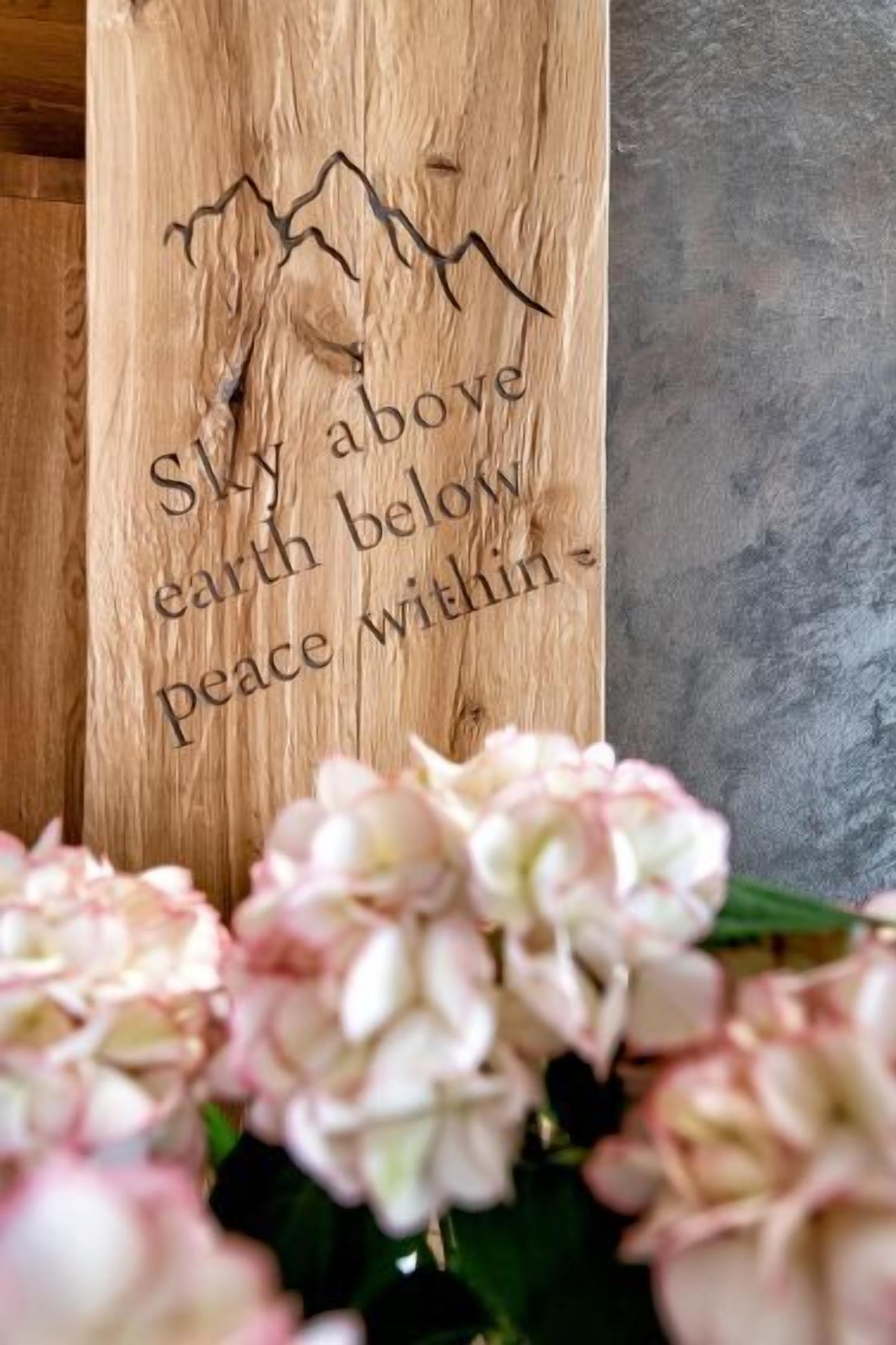 A wooden sign with a mountain design and the text "Sky above earth below peace within."