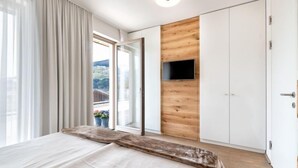 Una camera da letto con un letto, una parete rivestita in legno, una TV e un balcone con vista.