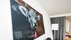 Ein modernes Wohnzimmer mit einem großen abstrakten Gemälde, einem dunkelgrauen Sofa und einer Lampe.