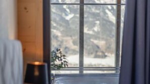 A bedroom with a large window offering a mountain view.