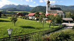 A rural village with a church, houses, and mountains in the background.
