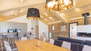 A modern interior with a wooden dining table, grey upholstered chairs, and a built-in fireplace. - Premium mit 4 Schlafzimmern,Sauna&Pool by Interhome (Haus)