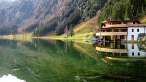 A lakeside cabin with a wooden deck and a boat dock, surrounded by mountains and dense forest. - Premium mit 4 Schlafzimmern,Sauna&Pool by Interhome (Haus)