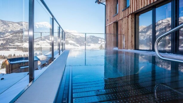A modern building with a glass balcony overlooking a snowy mountain landscape. - Premium mit 4 Schlafzimmern,Sauna&Pool by Interhome (Haus)
