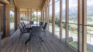 A wooden deck with a glass balustrade overlooking a mountainous landscape. - Premium mit 4 Schlafzimmern,Sauna&Pool by Interhome (Haus)