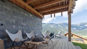 An outdoor seating area with stone walls and wooden flooring, overlooking a mountainous landscape. - Premium mit 5 Schlafzimmern, Sauna &Pool by Interhome (Haus)