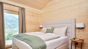 A bedroom with a bed, a nightstand, a lamp, and a view of the outdoors. - Premium mit 5 Schlafzimmern, Sauna &Pool by Interhome (Haus)