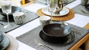 A dining table set with geometric patterned placemats, black plates, and clear glasses.