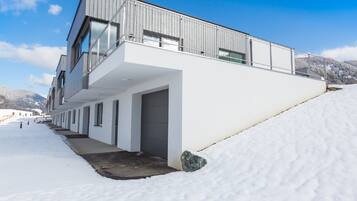 Un bâtiment moderne doté d’un toit plat, de grandes fenêtres et d’un sol recouvert de neige.