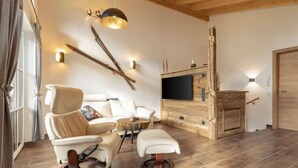 A modern living room with a sofa, chairs, a coffee table, and a TV mounted on a wooden wall. - Premium # 1A mit Sauna by Interhome (Uttendorf)